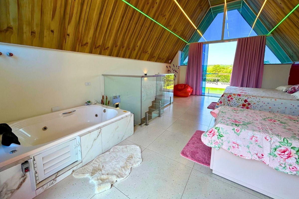 A modern bedroom with a large bed, a separate bathroom with a bathtub, and a view through a large window.