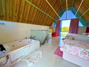 Un dormitorio moderno con una cama grande, un baño separado con bañera y vistas amplias a través de un ventanal.