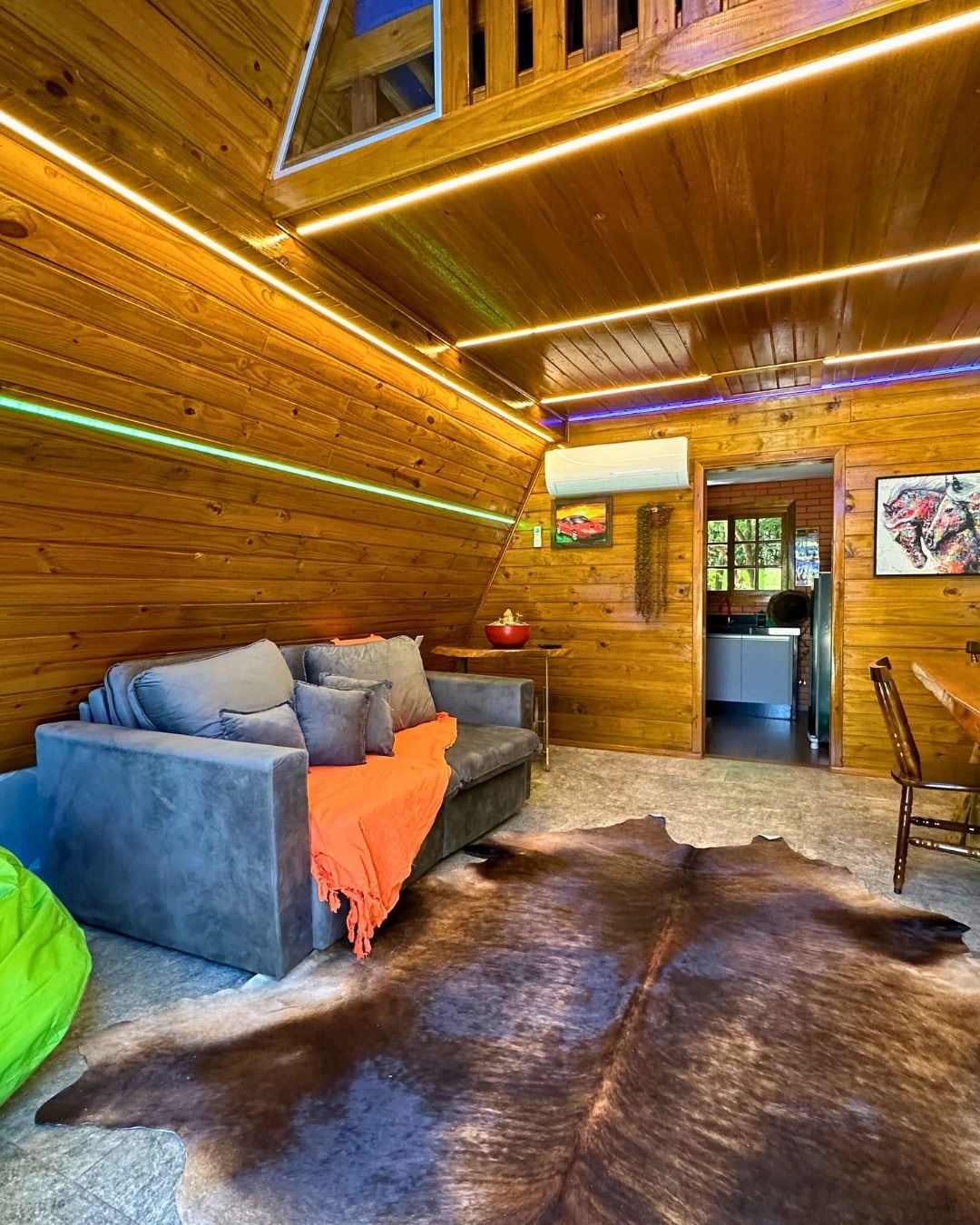 A cozy cabin interior with a sofa, a dining table, and a large fur rug.