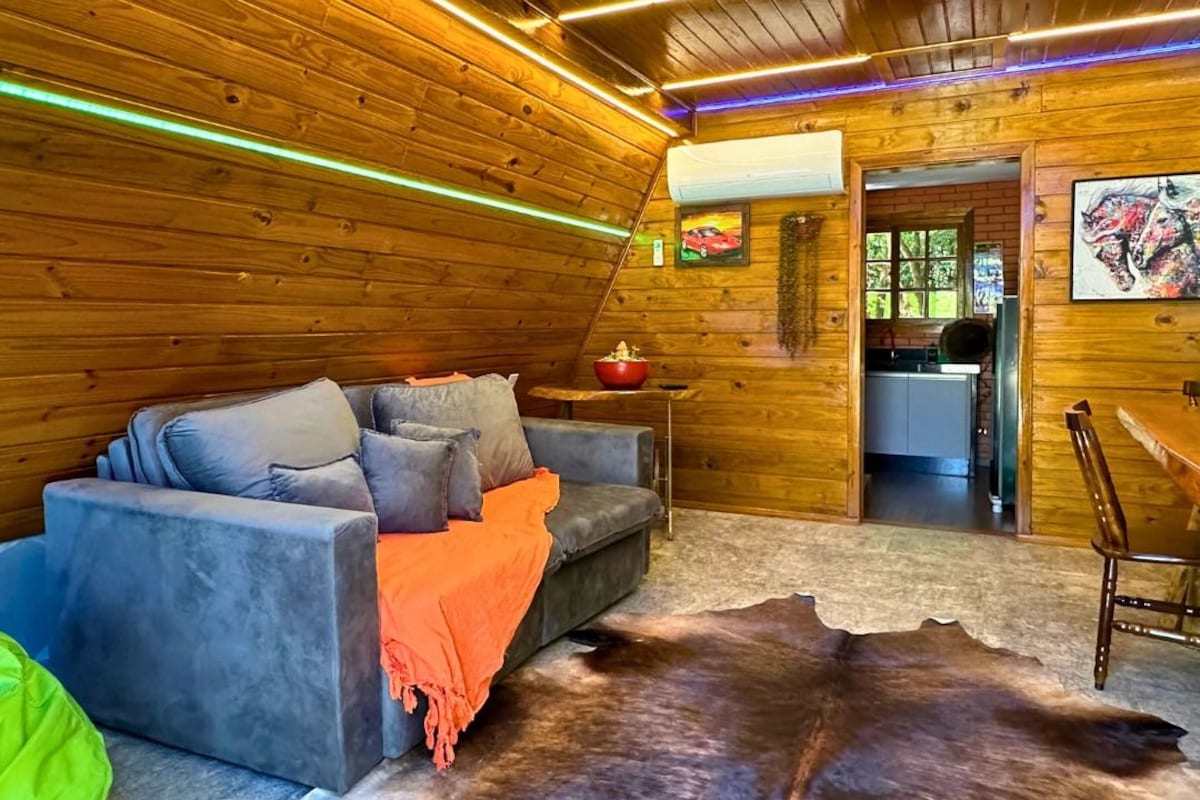 A cozy cabin interior with a sofa, a dining table, and a large fur rug.