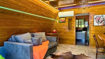 A cozy cabin interior with a sofa, a dining table, and a large fur rug.