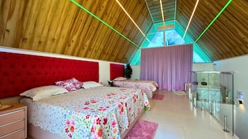 A bedroom with a sloped ceiling, a bed with floral bedding, a red headboard, and a glass cabinet.