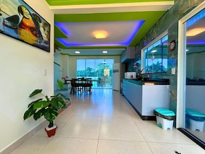 A modern kitchen with a dining area, large windows, and a green ceiling.