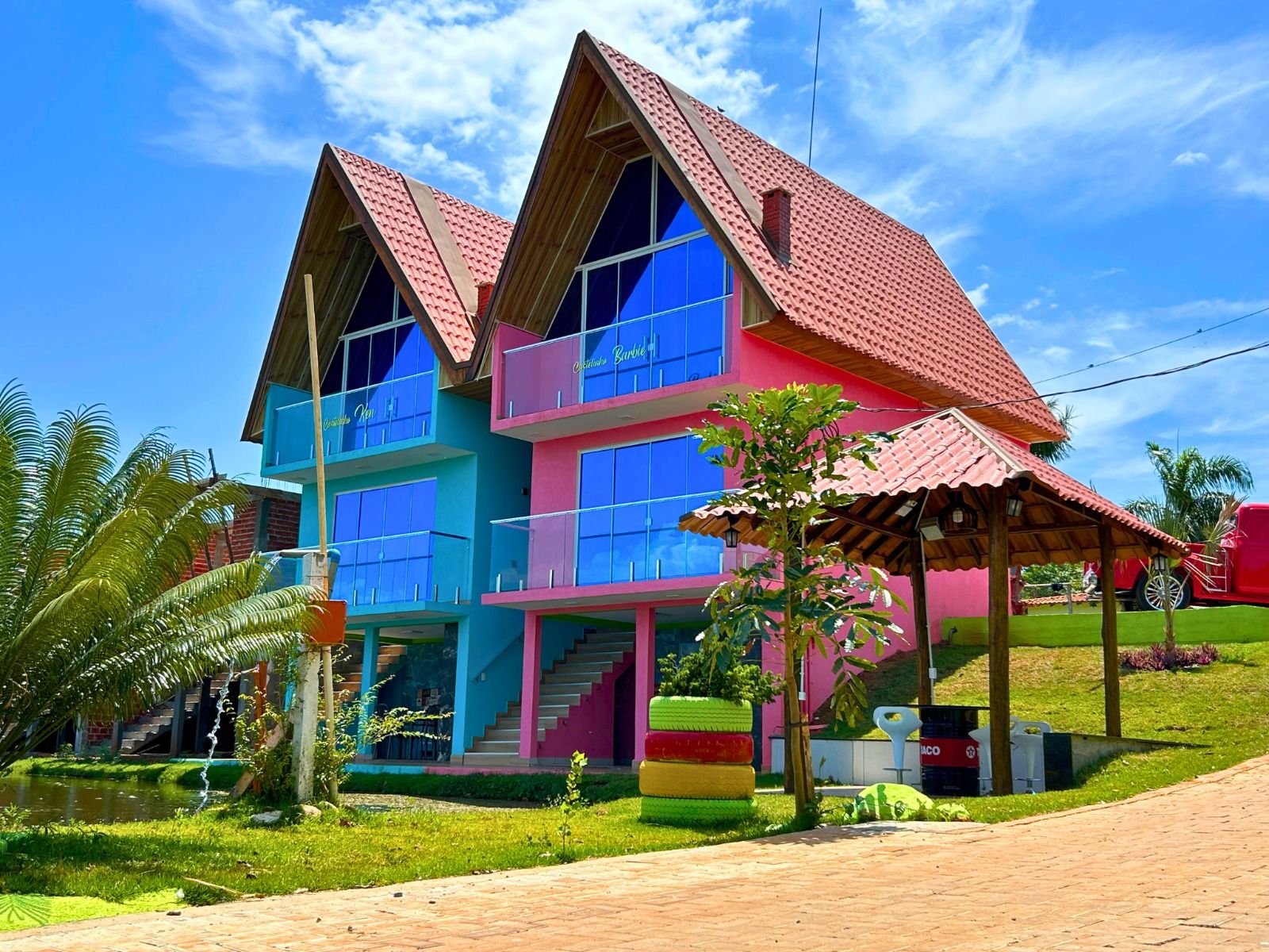 Un edificio de varios pisos con techo rojo, paredes azules y rosadas, y grandes ventanales.