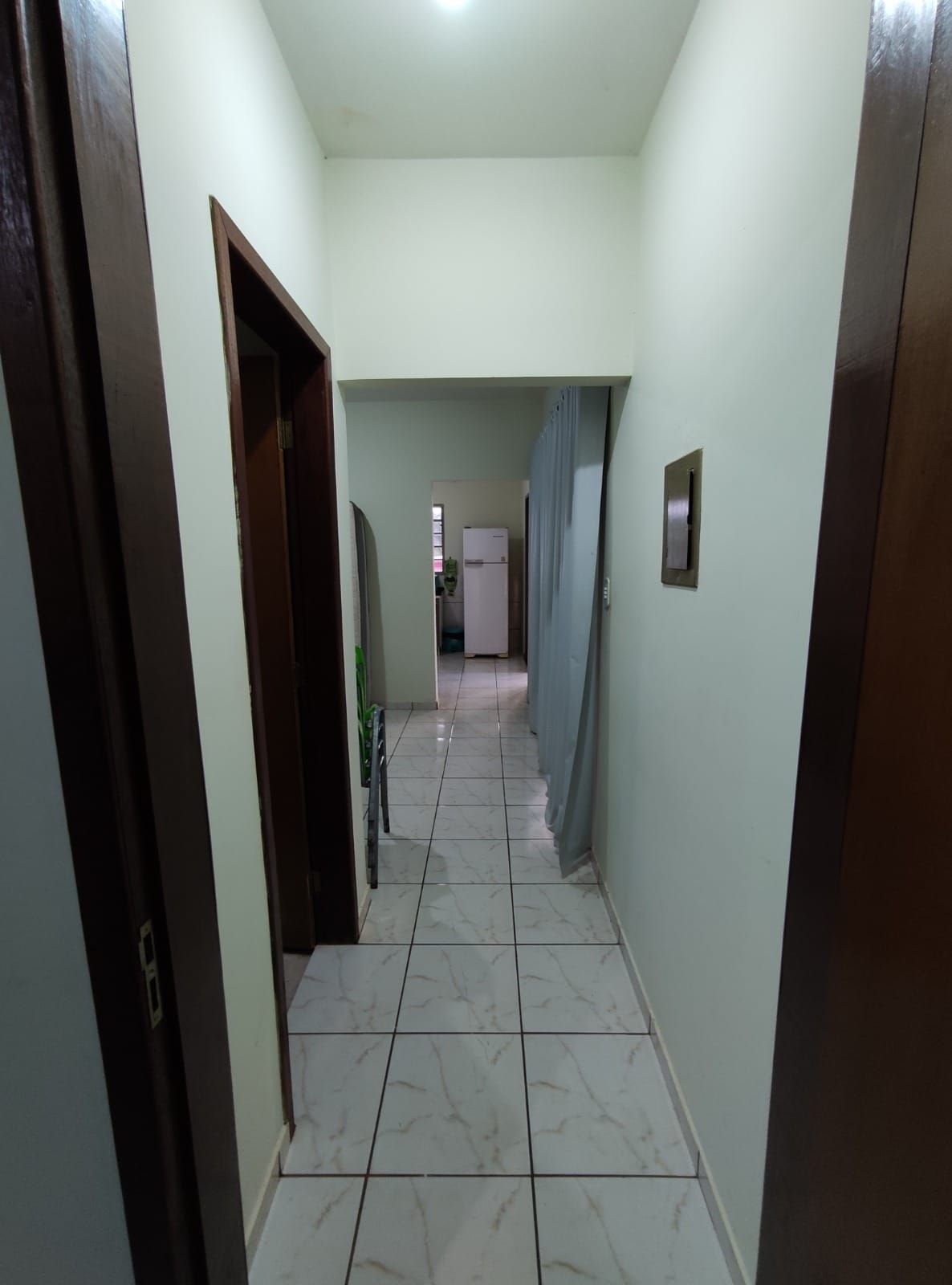 A hallway with a tiled floor leading to a kitchen area.