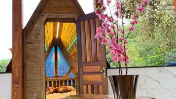 Estructura de madera con una puerta que da a una habitación con una cama y una ventana.