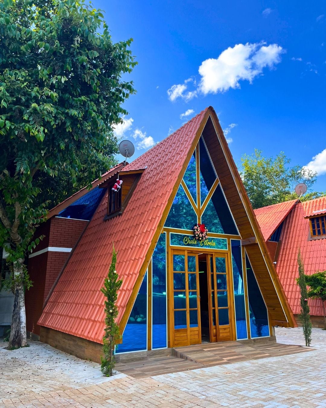 A triangular-shaped building with a red roof, a wooden door, and a sign that reads 'Chalet & Terre.'