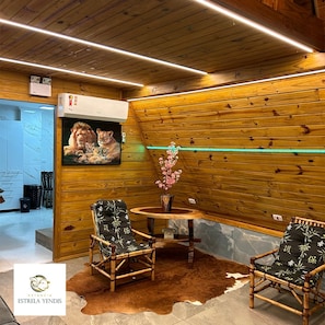 A room with wooden panel walls, a painting of lions, a small round table with chairs, and a logo on the floor.