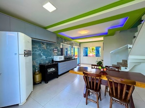 A modern kitchen with a built-in oven, microwave, and refrigerator. There is a dining area with wooden chairs and a table.