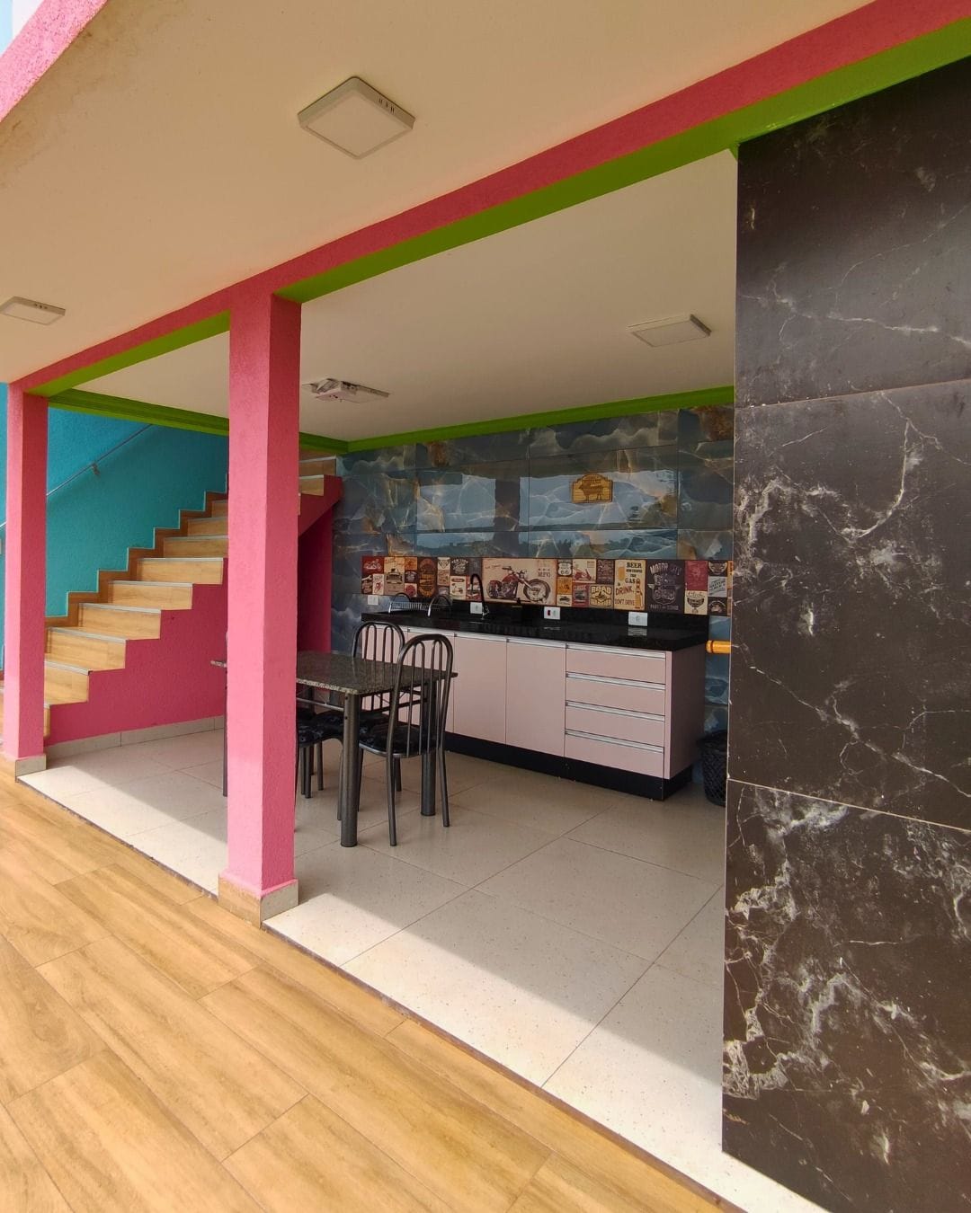 Eine Küche mit Fliesenrückwand, ein Essbereich mit Stühlen und eine Treppe mit blauer Wand.