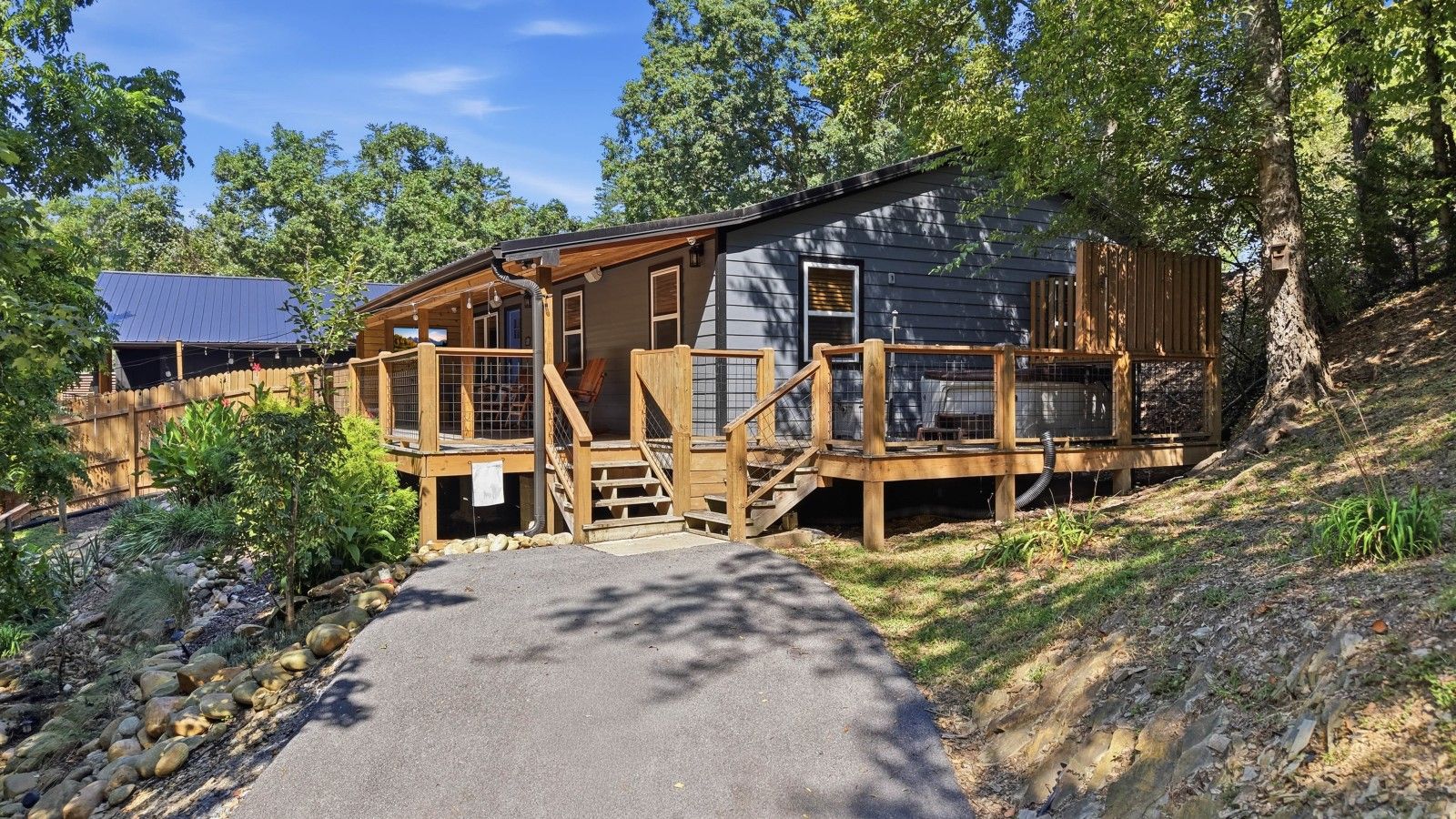 A cabin with a wooden deck, a covered porch, and a stone pathway leading to the entrance.