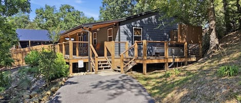 A cabin with a wooden deck, a covered porch, and a stone pathway leading to the entrance.