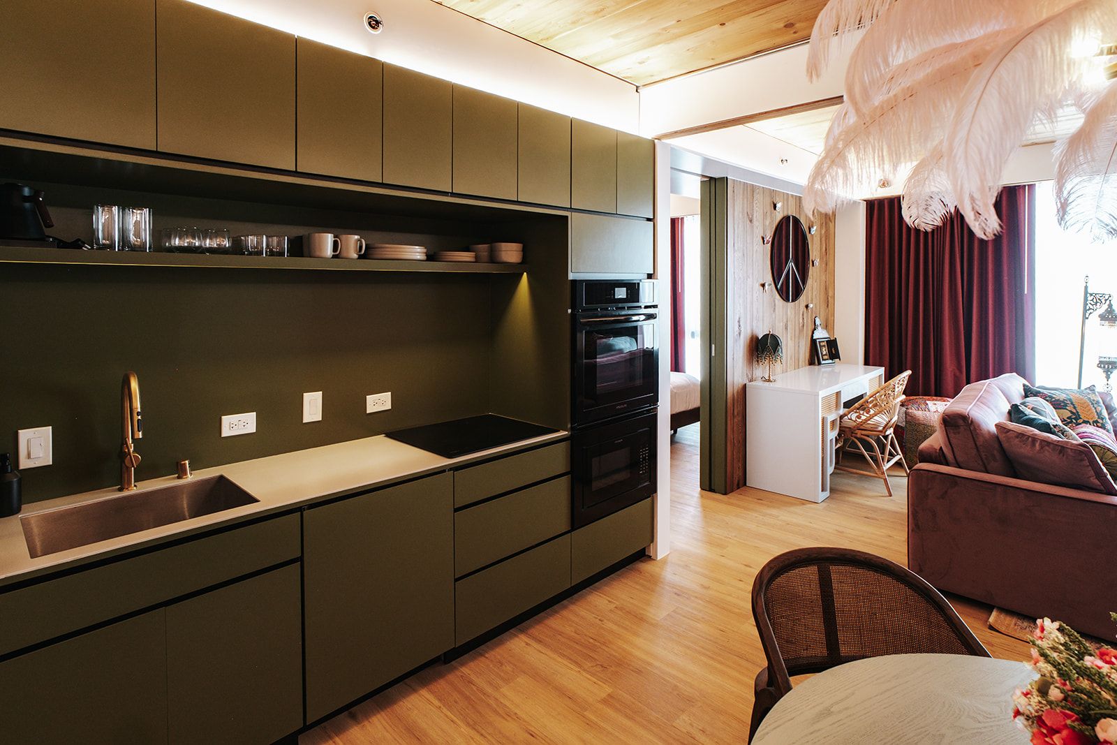 A modern kitchen with a built-in oven, a sink, and a dining area with a table and chairs.
