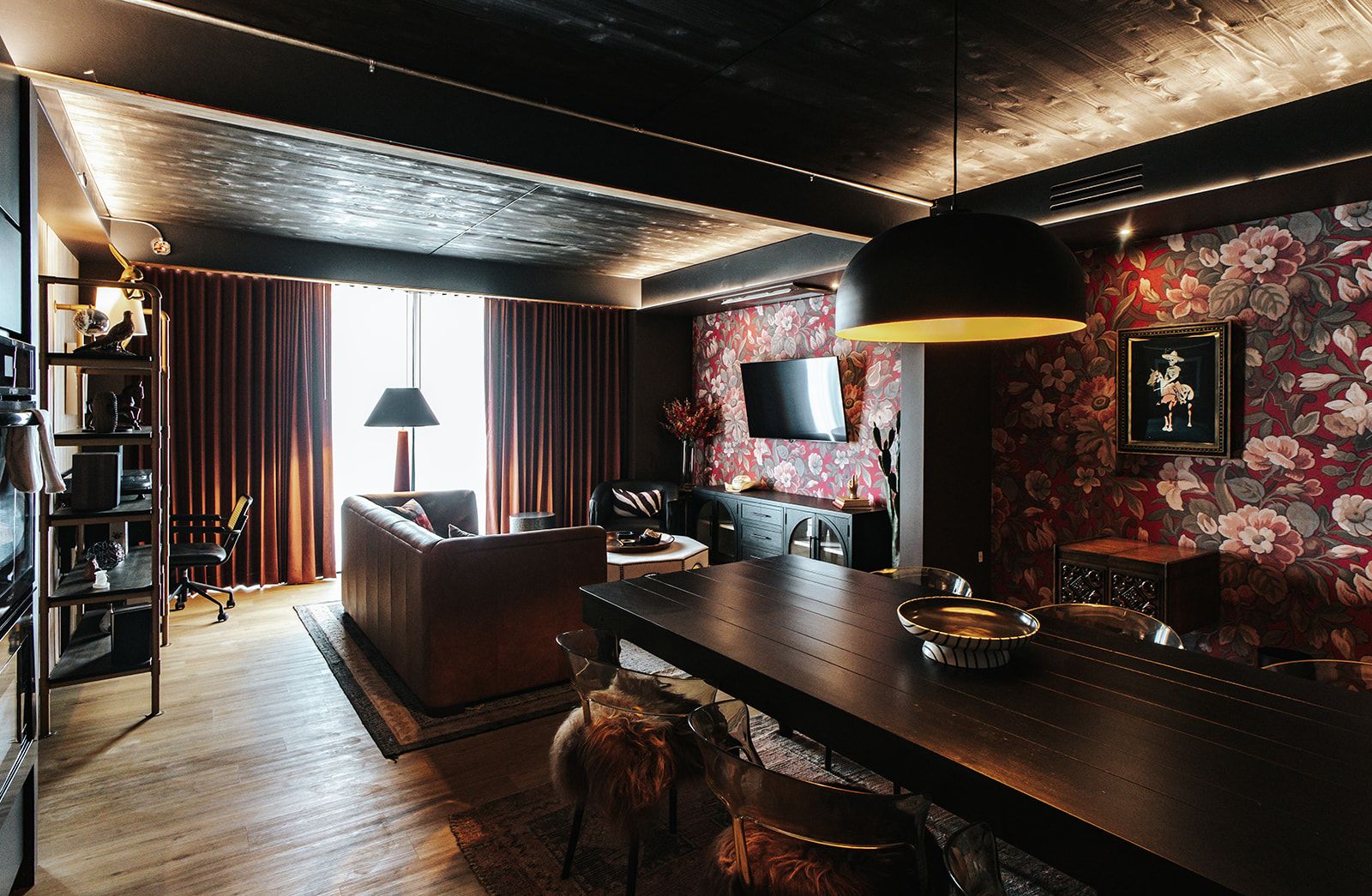Una sala moderna con sofá, una mesa de comedor y un televisor en la pared.
