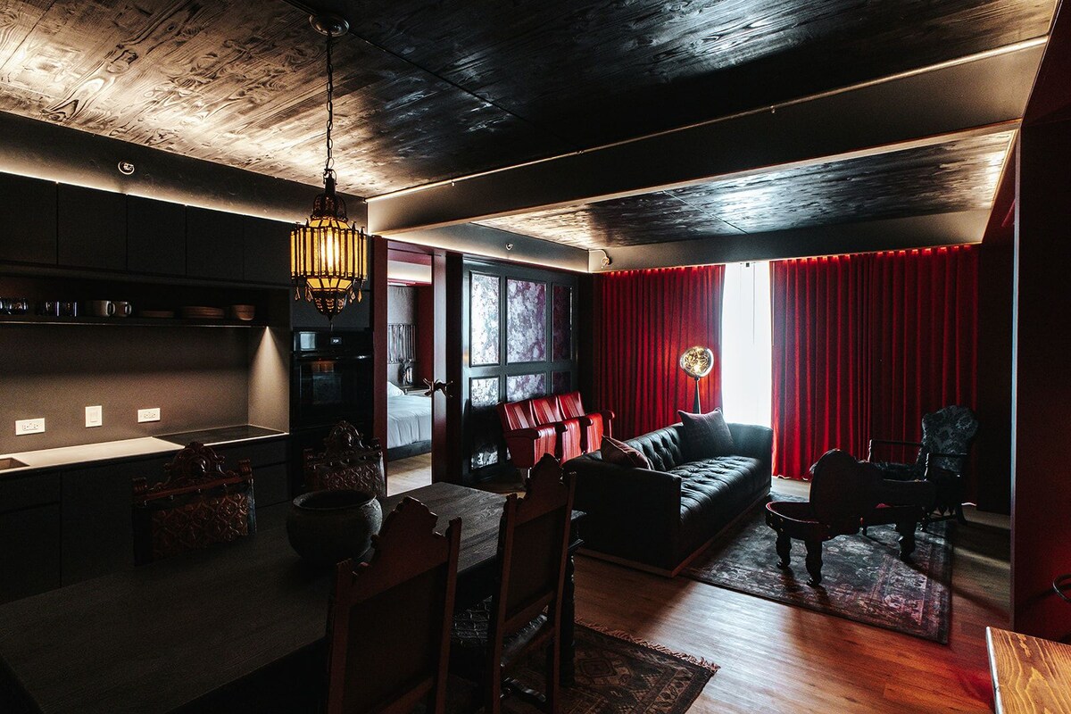 Un interior moderno con una zona de comedor, un sofá y una cortina roja.