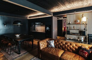 A modern interior with a leather sofa, dining table, and kitchen area.