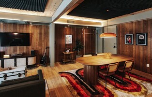 A modern living room with a wooden dining table, a television, and a guitar.