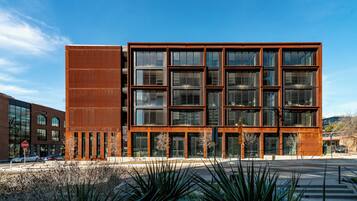 A modern building with a mix of glass and metal facade, featuring a prominent vertical metal panel on the left.