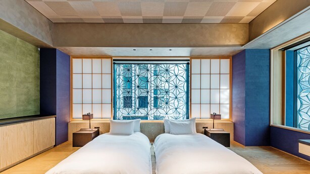 A modern hotel room with a large bed, two bedside tables, and a large window with a geometric pattern. - Playwright Test Hotel 1789146053536 (Seattle)