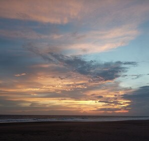 Ein Strand bei Sonnenuntergang, mit Wolken am Himmel.