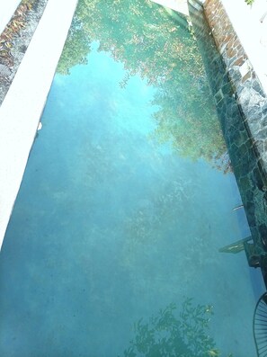 A clear view of a swimming pool with a tiled edge and a stone wall.