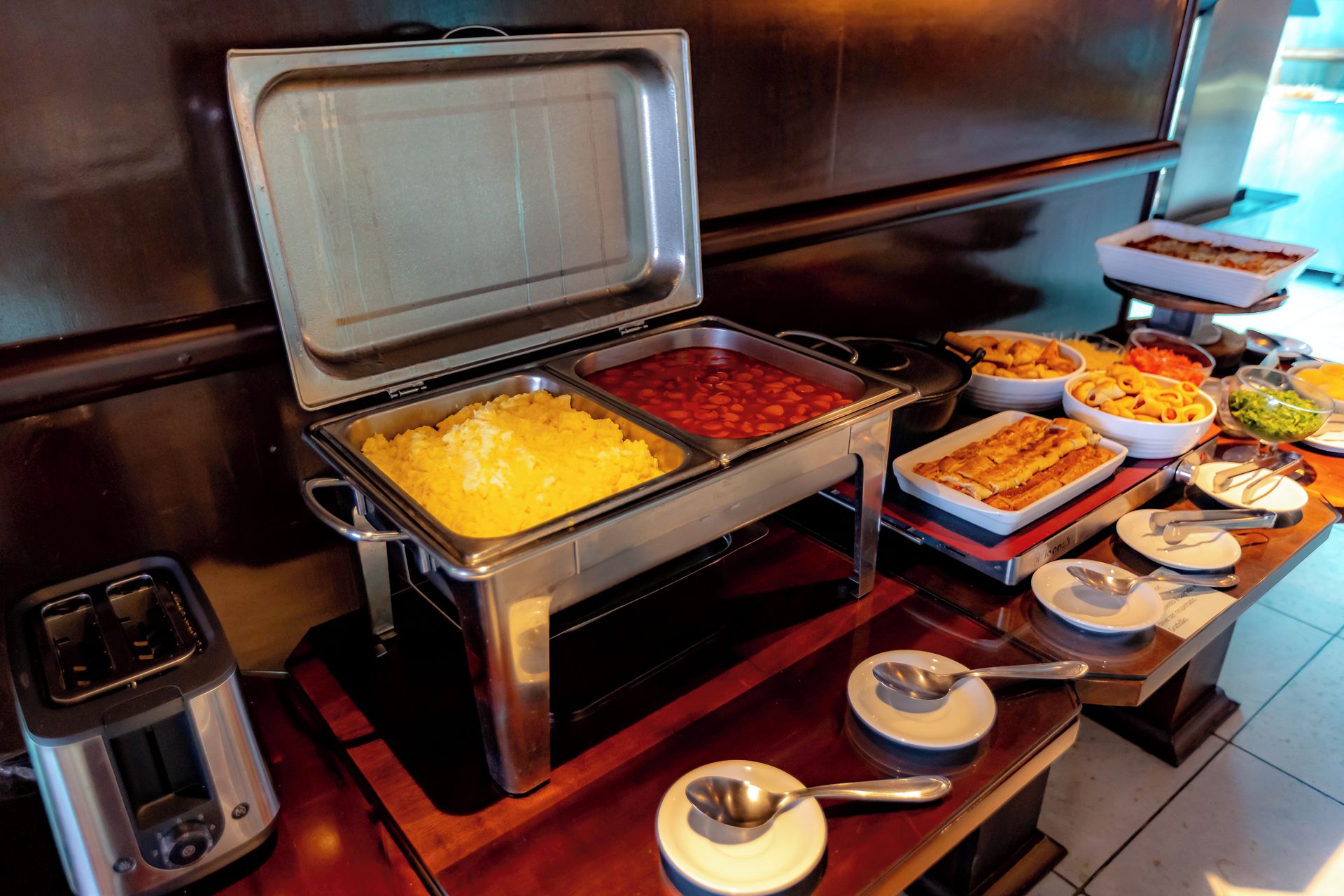 A buffet with various food options including potatoes, beans, and pasta.