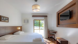 Ein Hotelzimmer mit Bett, Schreibtisch, Fernseher und einem Fenster mit Vorhängen.