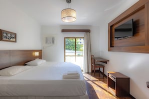 A hotel room with a bed, a desk, a television, and a window with curtains. - Costa Verde By Candeias (Bombinhas)