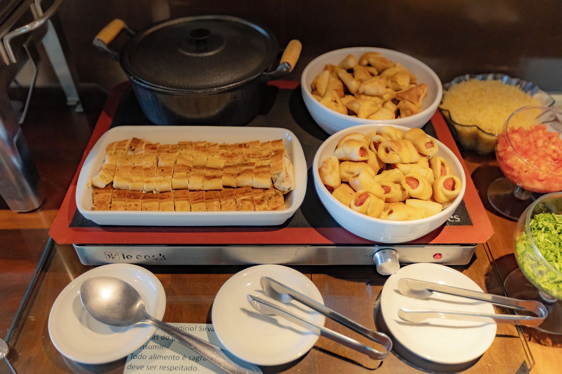A buffet table with various food items including a large rectangular dish of baked goods, bowls of appetizers, and a bowl of salad.