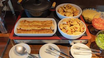 A buffet table with various food items including a large rectangular dish of baked goods, bowls of appetizers, and a bowl of salad.