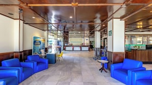 Eine Hotelhalle mit blauen Sitzgelegenheiten, einem Empfangsbereich und einem sichtbaren Restaurant.
