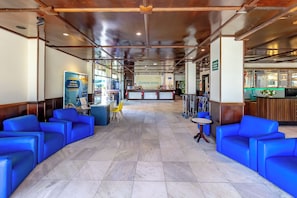 A hotel lobby with blue seating, a reception desk, and a visible restaurant area. - Costa Verde By Candeias (Bombinhas)