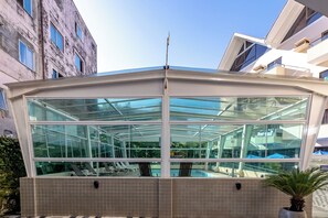 A modern building with a glass conservatory, a swimming pool, and a tiled exterior. - Costa Verde By Candeias (Bombinhas)