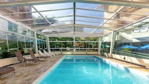 Ein klarer, gläserner Pool mit Liegestühlen und Blick ins Freie.