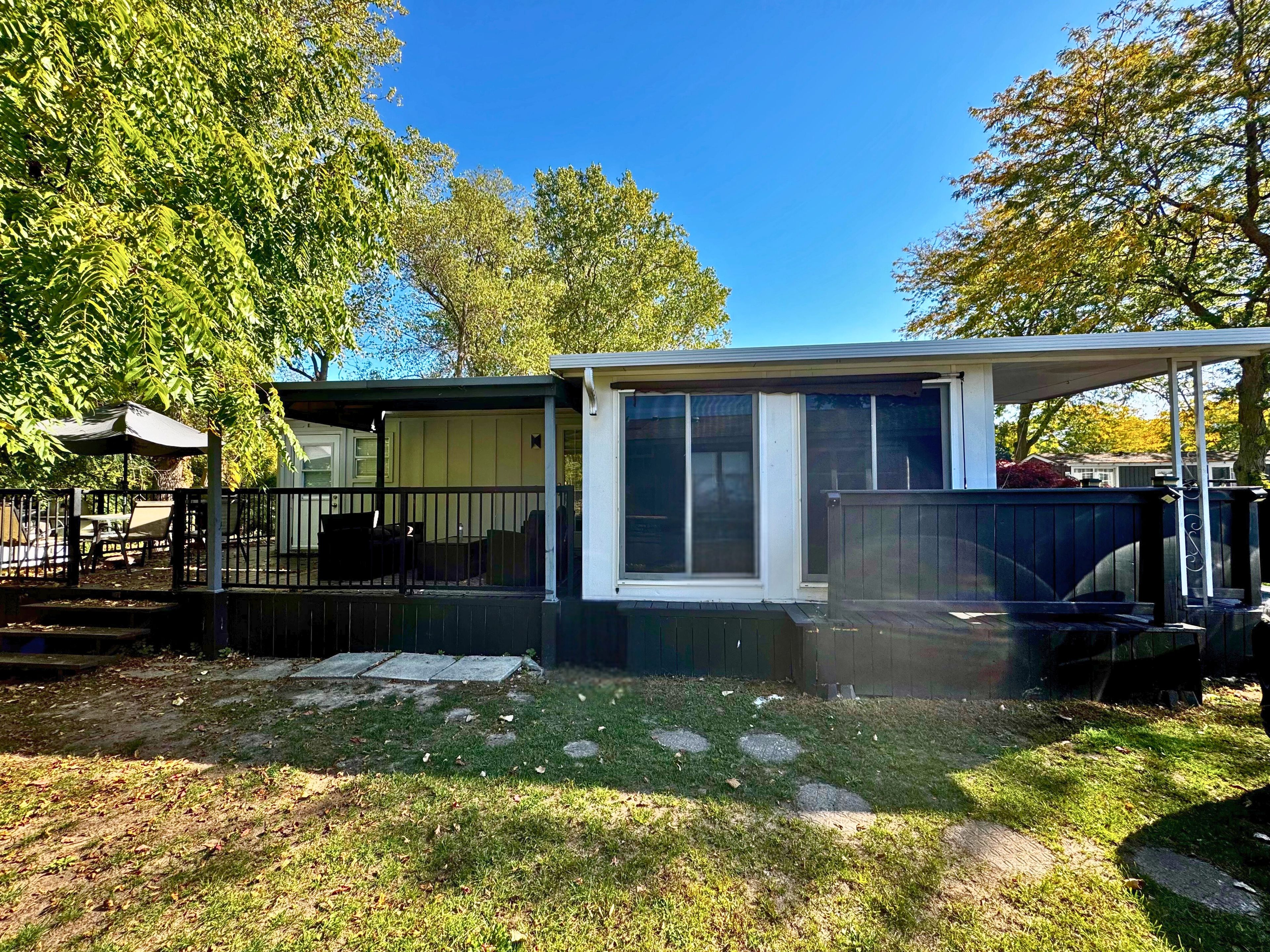 A single-story house with a covered patio, a fenced yard, and a lawn.