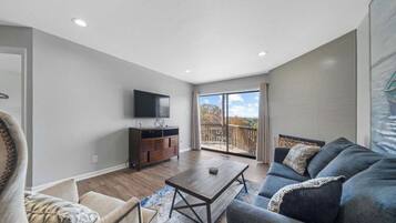 A spacious living room with a sofa, coffee table, and a flat-screen TV.