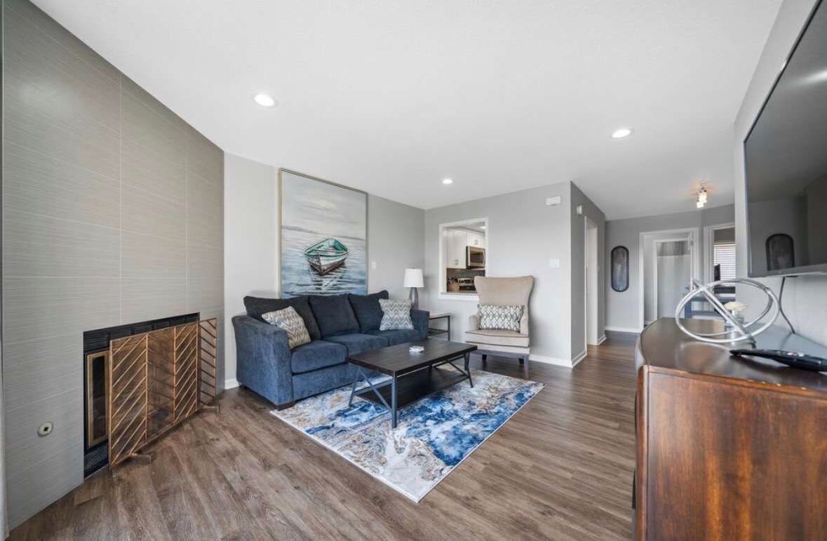 A modern living room with a blue sofa, a coffee table, and a rug.