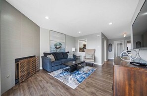 A modern living room with a blue sofa, a coffee table, and a rug. - Hamilton Harbor Hideaway | Lake Views & Pool (Hot Springs)