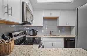 A modern kitchen with white cabinetry, a stainless steel range hood, a built-in microwave, and a dishwasher. - Hamilton Harbor Hideaway | Lake Views & Pool (Hot Springs)