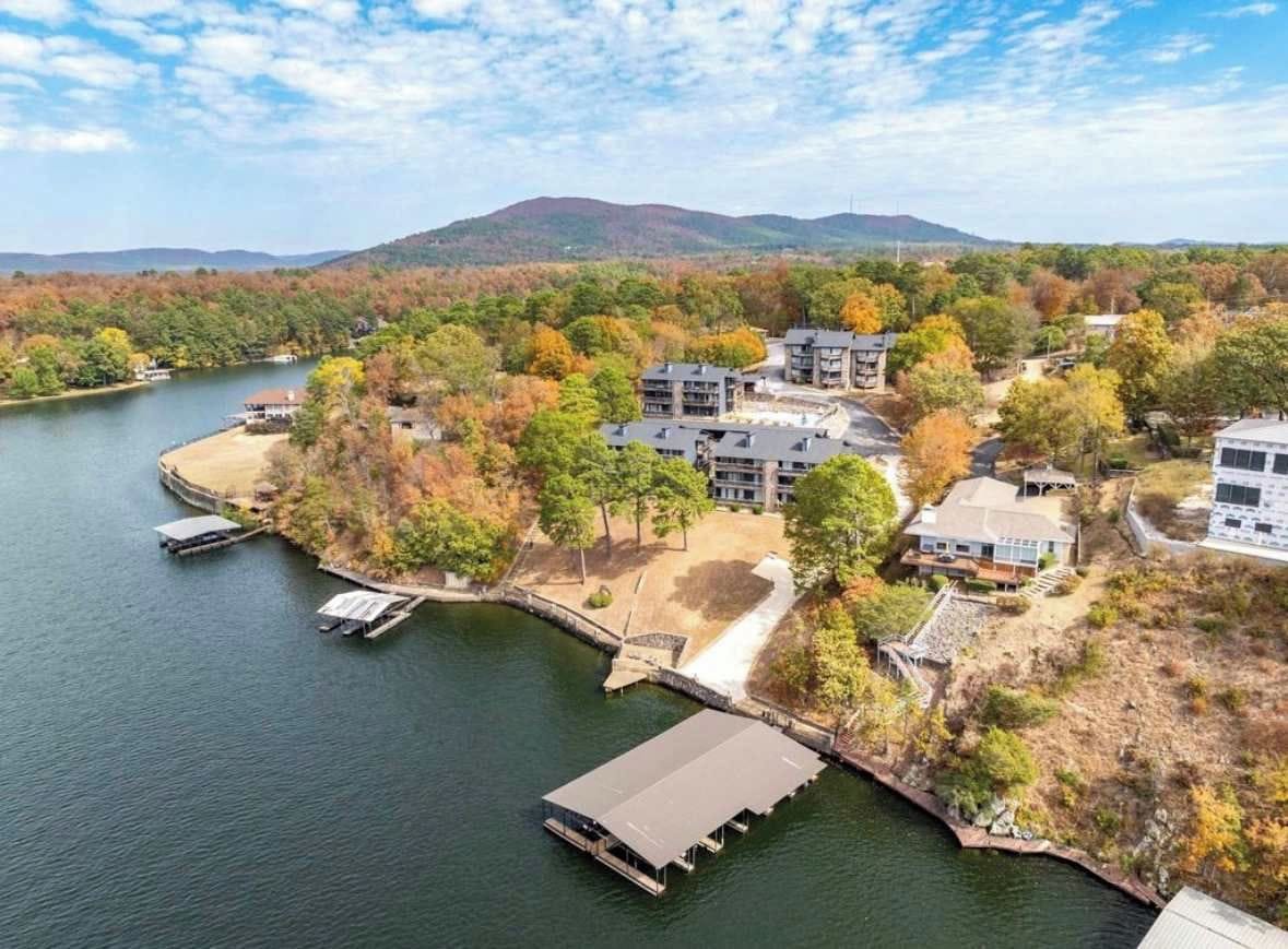 A lakeside property with multiple buildings, docks, and a docked boat.