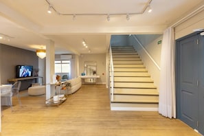 Een modern interieur met een trap, een flatscreentelevisie en een zithoek met een bank en salontafel.