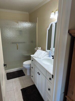 Een badkamer met douche, toilet en wastafel met spiegel.