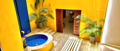 A small courtyard with a swimming pool, potted plants, and a wooden staircase.