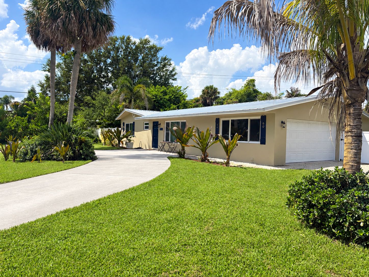 A single-story building with a curved driveway, surrounded by well-maintained grass and palm trees.