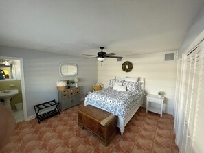 A bedroom with a bed, a nightstand, a dresser, a window, and a ceiling fan. - Tranquil Riverfront Retreat with Private Pool & Screened Lanai (Jensen Beach)