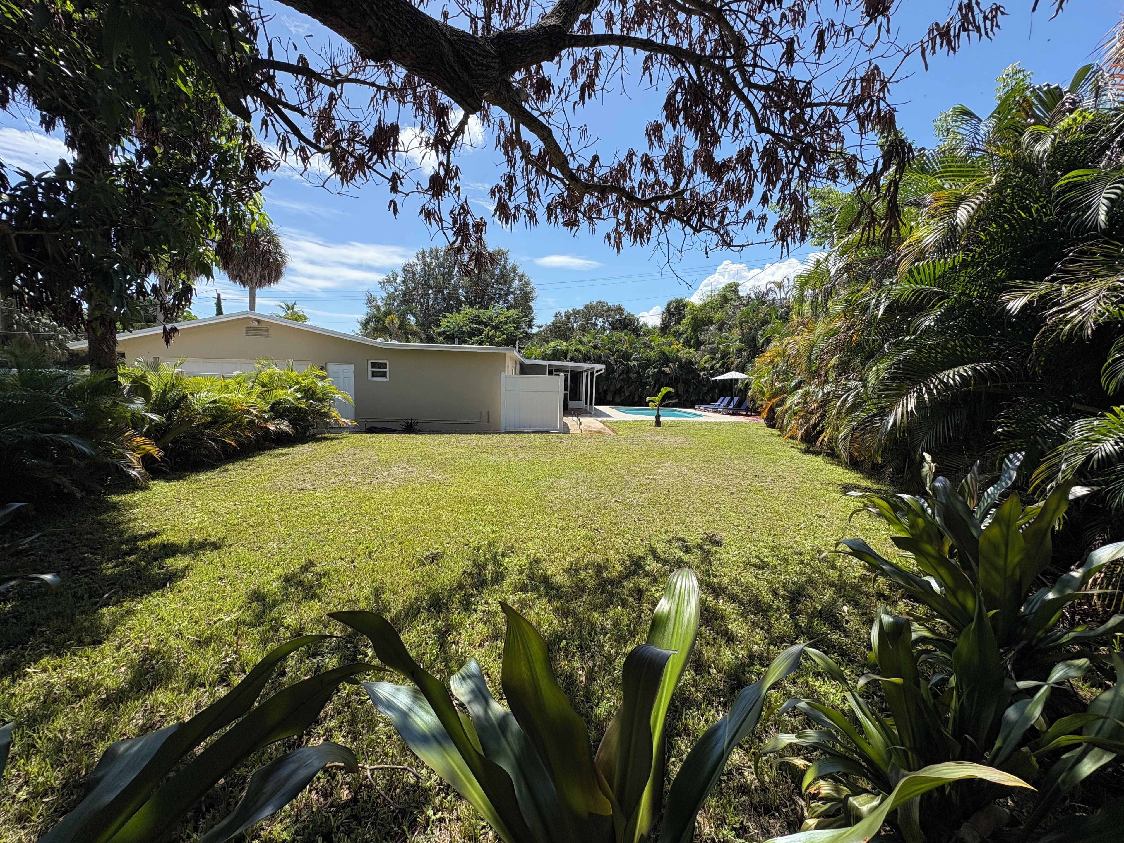 Una propiedad residencial con césped cuidado, piscina y zona de patio techada.