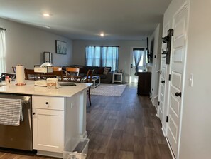 A modern kitchen with a central island, dining area with chairs, and a living space with a sofa and curtains. - Fun in the Sun and on the Golf Course (Conway)