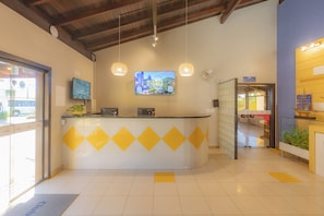 A reception area with a counter, a television, and a large poster on the wall.