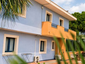 Un edificio de dos pisos con un balcón, ventanas y mobiliario exterior.