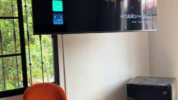 Un téléviseur fixé au mur affiche l’interface de Netflix, avec une affiche du film « Los Duenos del Juego » et une sélection de trois pièces.